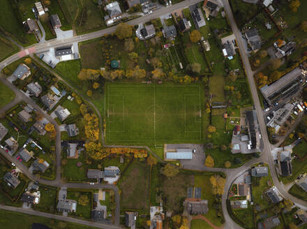 Aerial view of a football field surrounded by houses in countryside, Chimay, Hainaut, Belgium. - AAEF19381