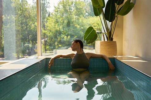 Woman with eyes closed relaxing in hot tub at spa - EKHF00035
