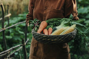 Frau hält Korb mit Gemüse im Garten - VSNF01254