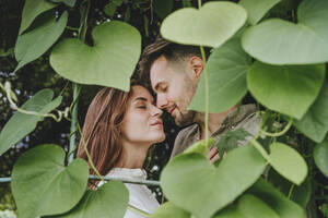Romantisches junges Paar inmitten von Pflanzen im Garten - YTF00911