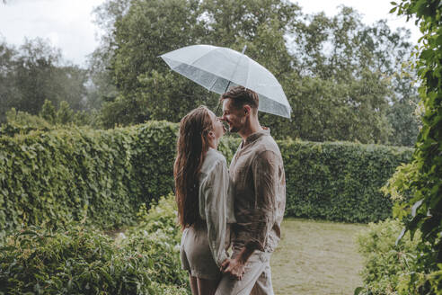 Romantic couple spending leisure time in rain at garden - YTF00929