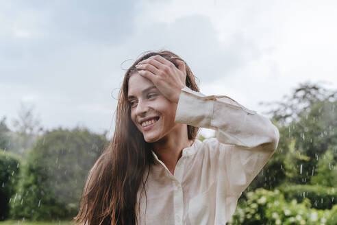 Contemplative woman standing in rain at garden - YTF00933