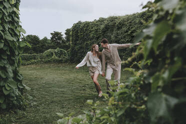 Glückliches Paar läuft im Garten - YTF00940