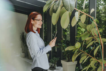 Happy redhead businesswoman standing with tablet PC - YTF00957