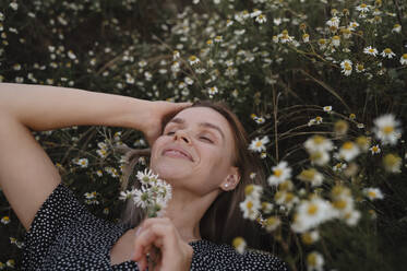 Frau mit Hand im Haar auf Blumen liegend - ALKF00531