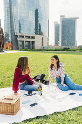 Smiling friends enjoying picnic in front of buildings - MEUF09161
