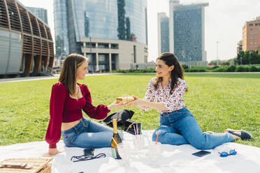 Glückliche Freunde genießen gemeinsam ein Picknick an einem sonnigen Tag - MEUF09163