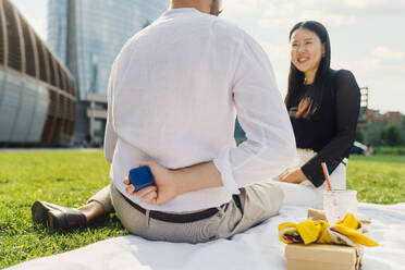 Man hiding jewelry box behind back in front of happy woman - MEUF09184