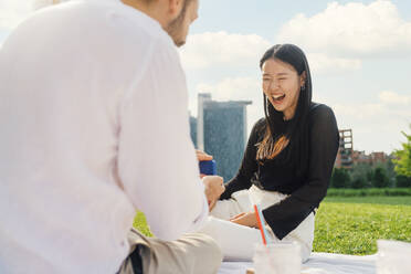 Man surprising happy woman with gift on sunny day - MEUF09186