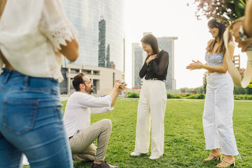 Glücklicher Mann macht Frau einen Heiratsantrag mit Ring vor einem Gebäude - MEUF09204