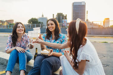 Cheerful friends toasting wineglasses together at sunset - MEUF09269