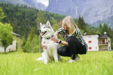 Woman crouching by dog on grass - NJAF00481