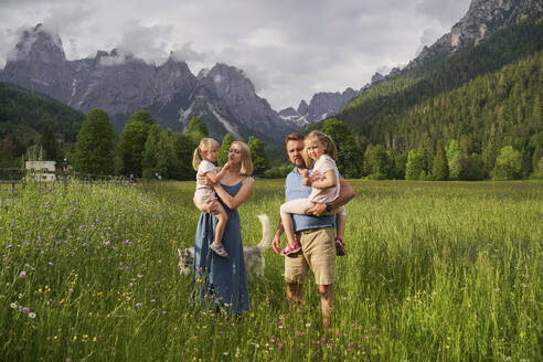 Vater und Mutter mit Töchtern vor einem Gebirge stehend - NJAF00483