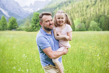 Lächelnder Mann mit Tochter, der inmitten von Pflanzen spazieren geht - NJAF00494