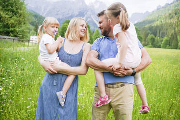 Man and woman looking at each other carrying daughters - NJAF00497