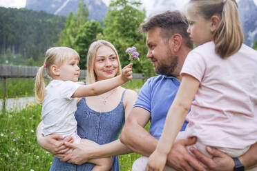 Mädchen zeigt dem Vater, der seine Tochter trägt, eine Blume - NJAF00498