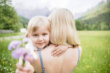 Blonde Frau mit Tochter, die eine Blume hält - NJAF00499