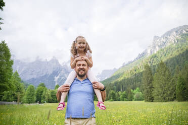 Glücklicher Mann, der seine Tochter auf den Schultern trägt, vor einem Gebirge - NJAF00502