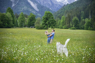 Romantic couple standing on grass in front of mountains - NJAF00510