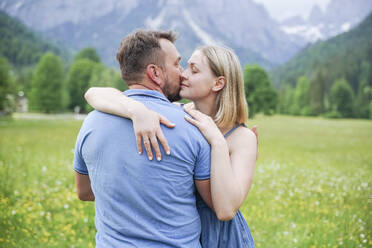 Affectionate man kissing woman in front of mountains - NJAF00515