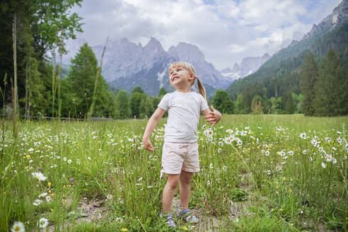 Carefree girl standing amidst plants in meadow - NJAF00523