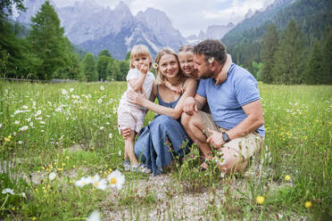 Töchter umarmen Vater und Mutter kauernd auf der Wiese - NJAF00525