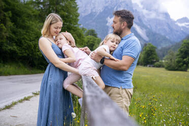 Parents with daughters sitting on railing - NJAF00531