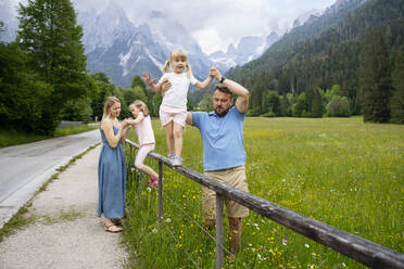 Parents supporting daughters playing on railing - NJAF00532