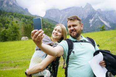 Eine dreiköpfige Familie hält einen Moment in den atemberaubenden Dolomiten, Italien, mit einem Selfie in ihrer Babytrage fest - NJAF00535