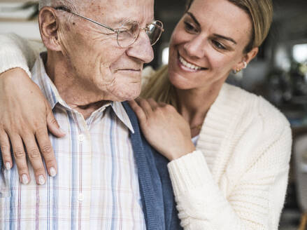 Smiling daughter taking care of senior man at home - UUF29893