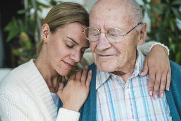 Smiling woman embracing senior man at home - UUF29895