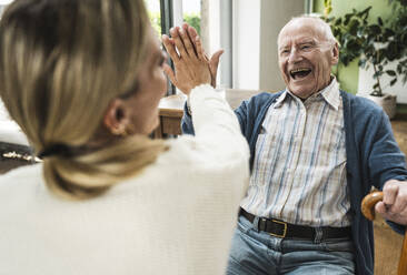 Cheerful father giving high-five to daughter at home - UUF29921