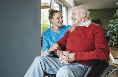 Glückliche Krankenschwester, die sich um einen älteren Mann zu Hause kümmert - UUF29961