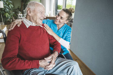 Smiling nurse taking care of senior man at home - UUF29962