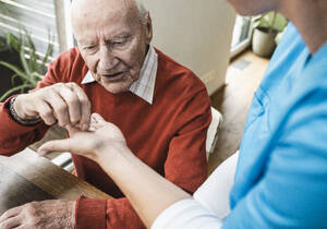 Krankenschwester gibt Medikamente und kümmert sich um einen älteren Mann zu Hause - UUF29970