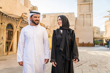 Arabisches Paar mit traditionellem emiratischem Kleid, das sich im Freien verabredet - Glückliches mittelöstliches Paar, das Spaß hat - DMDF00437