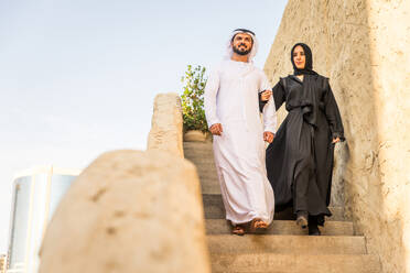 Arabisches Paar mit traditionellem emiratischem Kleid, das sich im Freien verabredet - Glückliches mittelöstliches Paar, das Spaß hat - DMDF00441