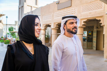 Arabisches Paar mit traditionellem emiratischem Kleid, das sich im Freien verabredet - Glückliches mittelöstliches Paar, das Spaß hat - DMDF00442