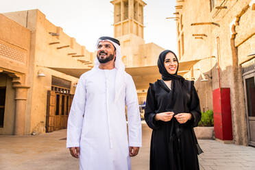 Arabisches Paar mit traditionellem emiratischem Kleid, das sich im Freien verabredet - Glückliches mittelöstliches Paar, das Spaß hat - DMDF00446