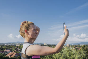 Smiling woman taking selfie under blue sky - OSF01924