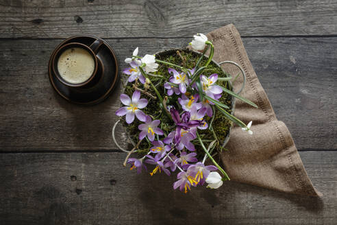 Tasse Kaffee und Frühlingsblumen in Metalleimer auf Holztisch stehend - EVGF04344