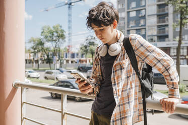 Teenage boy using smart phone in city - ANAF01897