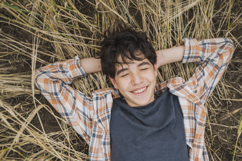 Smiling boy lying on hay - ANAF01905