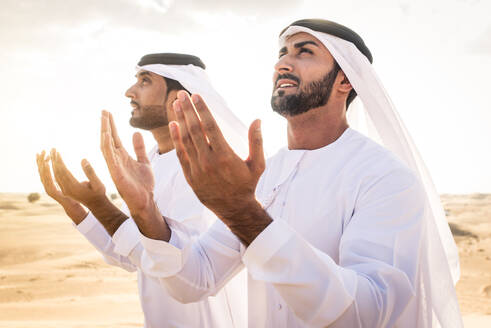 Arabische Männer mit Kandora beim Spaziergang in der Wüste - Porträt von zwei Erwachsenen aus dem Nahen Osten in traditioneller arabischer Kleidung - DMDF00536