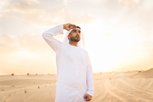 Arabische Männer mit Kandora beim Spaziergang in der Wüste - Porträt von zwei Erwachsenen aus dem Nahen Osten in traditioneller arabischer Kleidung - DMDF00538