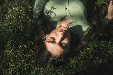 Frau mit geschlossenen Augen im Gras liegend - YBF00072