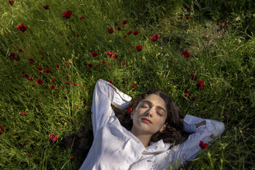 Frau entspannt sich im Gras mit Mohnblumen - YBF00075