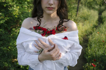 Young woman with poppy flowers in white shirt - YBF00077