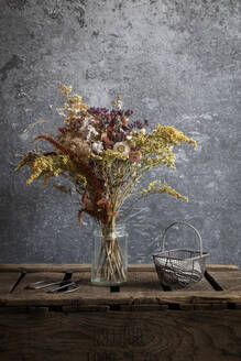 Arrangement aus getrockneten Blumen in einem auf einer Holzkiste stehenden Glas - EVGF04353