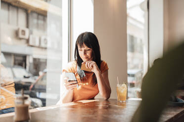 Lächelnde Frau mit Kreditkarte und Mobiltelefon in einem Cafe - JOSEF20408